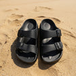 Black buckle slides on a sandy surface