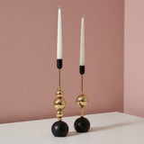 Matte black spheres and cups with polished gold beads between, holding white tapers