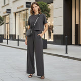 Woman in a grey outfit standing on a city street with shops in the background