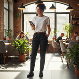 Woman wearing black pants and a white tshirt in a modern cafe with large windows and plants