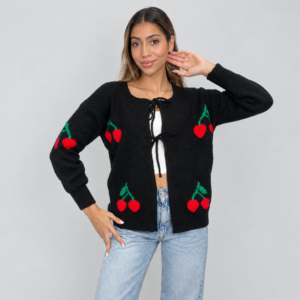 Black cherry knit cardigan with bow ties, one hand raised to the hair