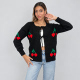 Black cherry knit cardigan with bow ties, one hand raised to the hair