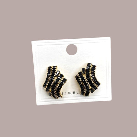 Pair of black and gold earrings on a display card against a beige background