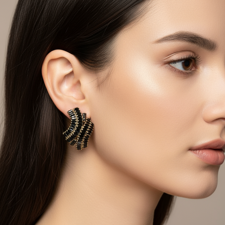 Close-up of a woman wearing a black and gold earring against a neutral background