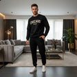 Man wearing a black 'Chicago' sweatshirt and pants in a modern living room
