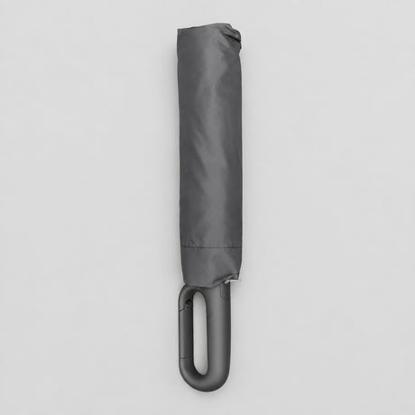 Folded charcoal black compact umbrella with a looped hook handle on a light grey background