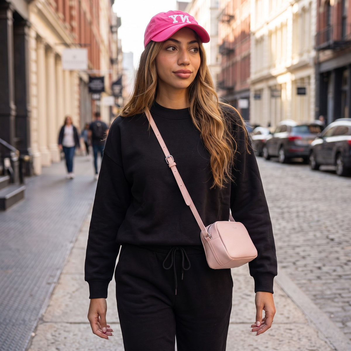 Woman walking a city street in a black crewneck sweatshirt and drawstring sweatpants