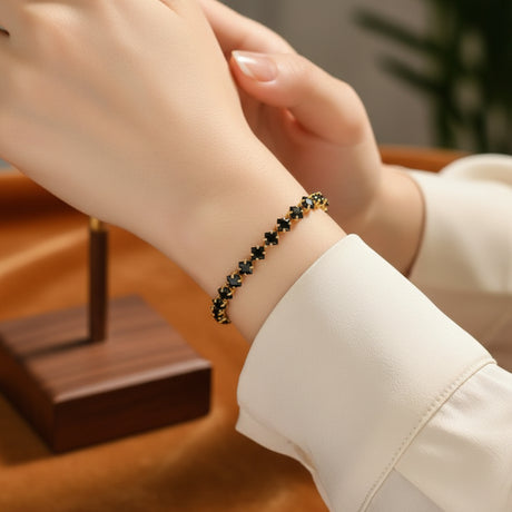 Black beaded tennis bracelet with a gold clasp worn by a person