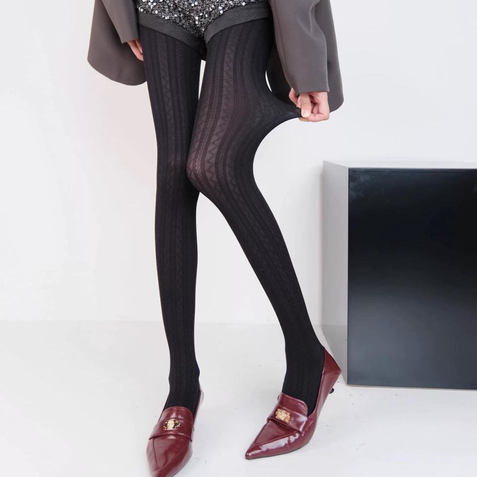 Person wearing black collant and red shoes standing on a white background