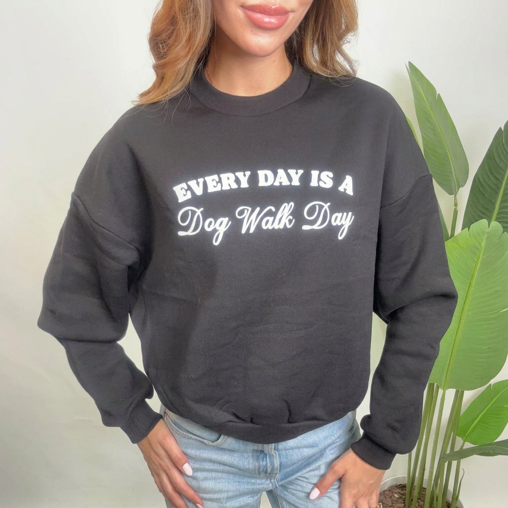 Close up of a black sweatshirt with a white Every Day Is A Dog Walk Day print and dropped shoulders