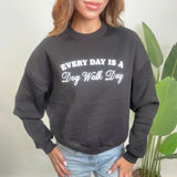 Close up of a black sweatshirt with a white Every Day Is A Dog Walk Day print and dropped shoulders