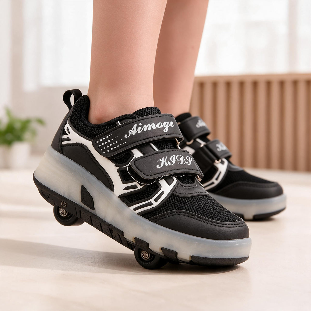 Black kids roller shoes with two hook and loop straps and a translucent sole, worn standing on a wooden floor