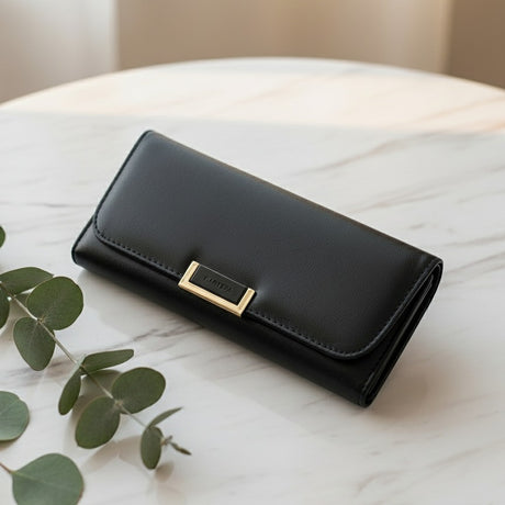 Black wallet with a gold clasp on a marble surface with leaves