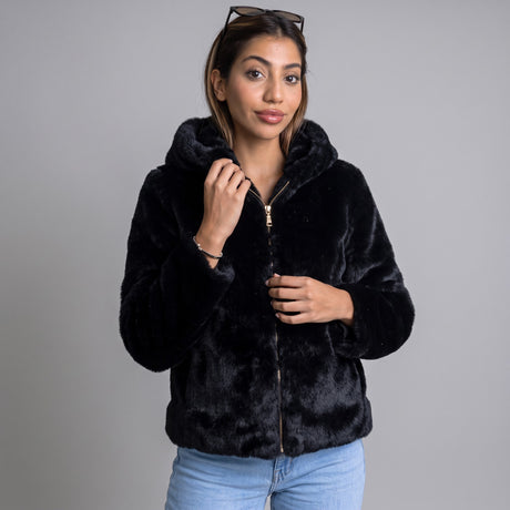 Black plush faux fur hooded jacket with a gold zip worn open over light blue jeans
