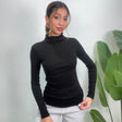 Black stretch turtleneck top in a body skimming fit, worn untucked over grey joggers