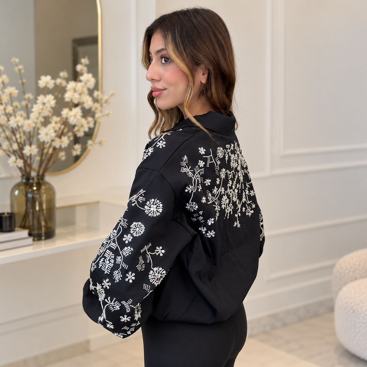 Side back view of the black bomber showing beaded flowers across the back shoulder and sleeve