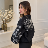 Side back view of the black bomber showing beaded flowers across the back shoulder and sleeve