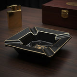 Side angle of the black ceramic ashtray showing its grooved rests and gold rim lines
