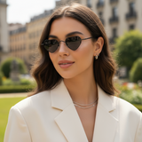 Woman wearing black heart-shaped sunglasses and a white blazer outdoors