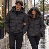Couple walking on a wet city pavement in matching black hooded puffer jackets