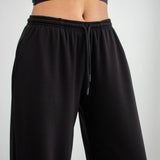 Black sweatpants worn by a person on a light gray background