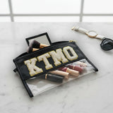 Makeup pouch with 'KTMO' branding on a marble surface with makeup items inside