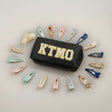 Black pouch with 'KTMO' text surrounded by various hair clips on a light grey background
