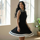 Woman wearing a black dress with white trim in a bright room