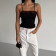 Person wearing a black top and white pants with a plain background