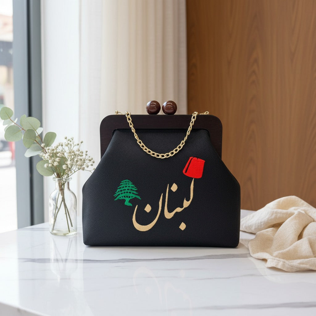 Black Lebanon frame bag styled on marble beside a vase of eucalyptus