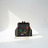 Black pebbled frame bag with wooden ball clasps, a green cedar and gold Arabic lettering