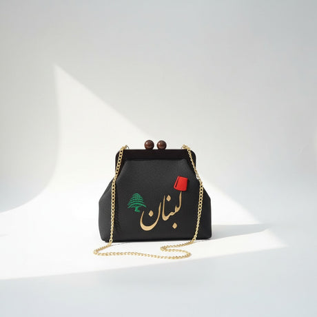 Black pebbled frame bag with wooden ball clasps, a green cedar and gold Arabic lettering