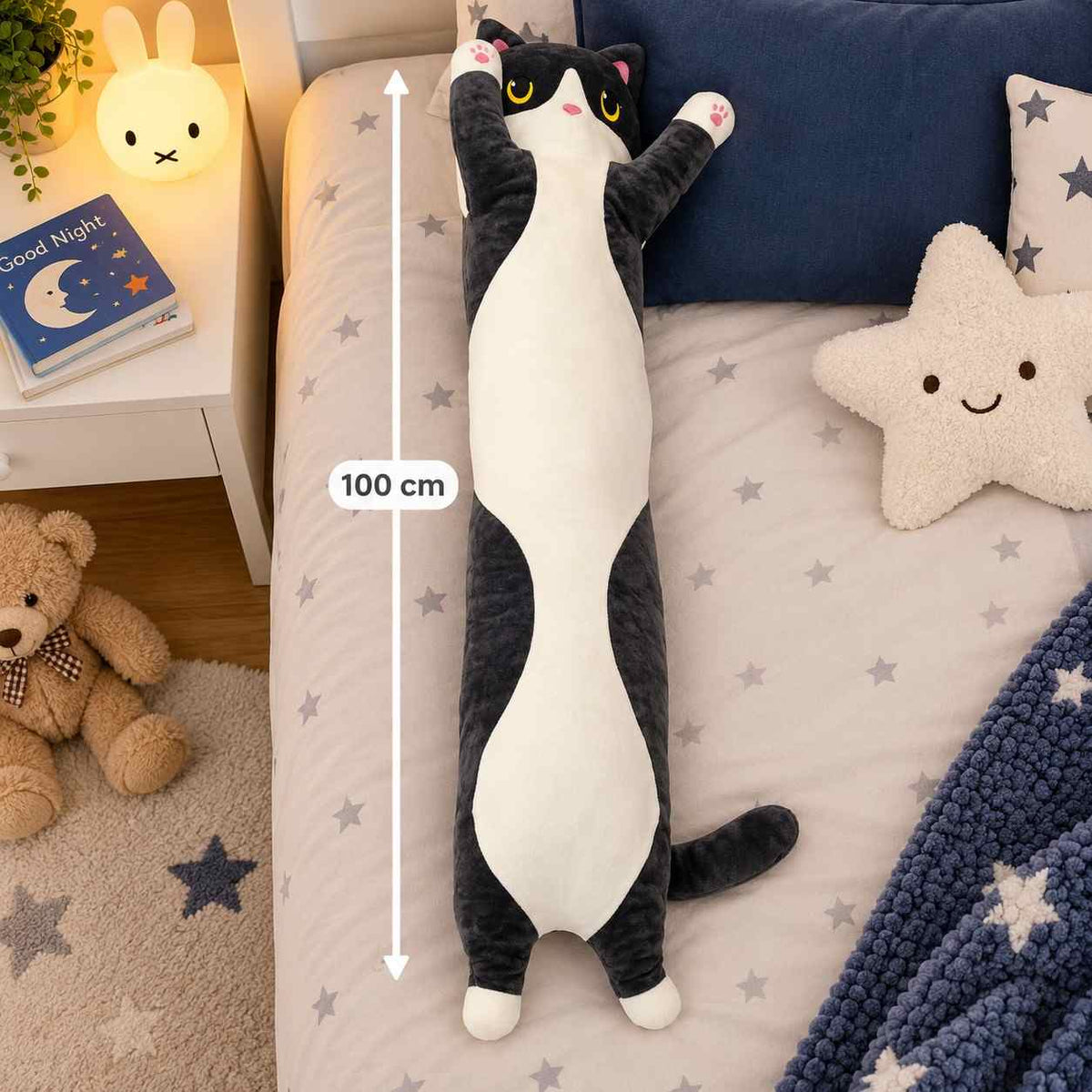 Black and white long cat body pillow plush on a star print bed with a 100 cm measuring line