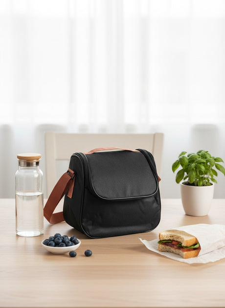 Black bag on a table with a water bottle, bowl of blueberries, and sandwich