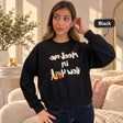 Woman in a black Meet me in New York sweatshirt with cream lettering and cherries, hand at her ear