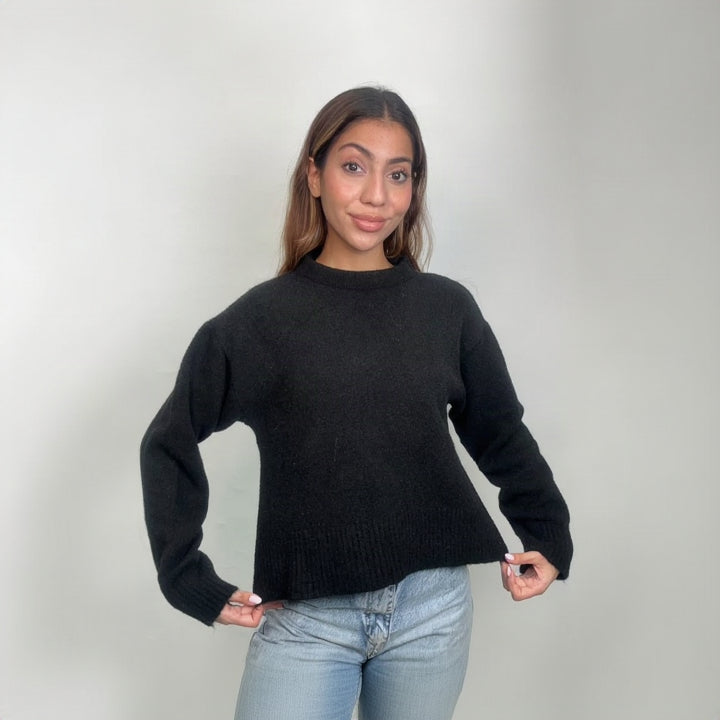 Black cropped mock neck knit sweater, holding the deep ribbed hem