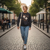 Woman wearing a black sweatshirt with oatmeal embroidered mushrooms and orange lettering