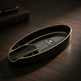 Slim black oval tray for one cigar, white dot grid inside and gold lines on both rims