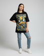 Person wearing a black graphic tshirt with a yellow duck graphic and ripped jeans on a plain background