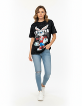 Woman wearing a black tshirt with a graphic bunny design and light blue jeans on a white background