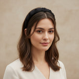 Black padded headband worn with shoulder length hair against a beige wall