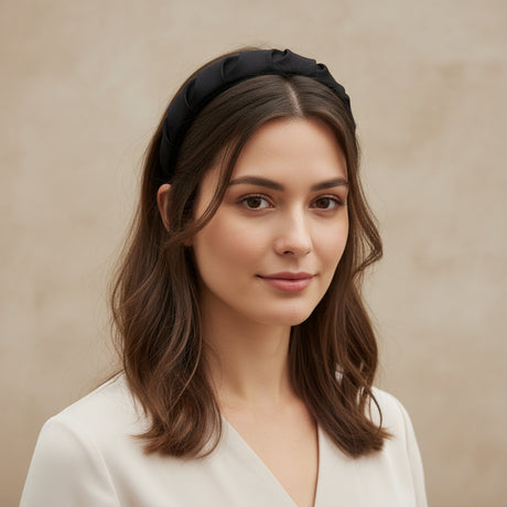 Black padded headband worn with shoulder length hair against a beige wall