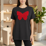 Woman wearing a black tshirt with a red butterfly design in an indoor setting