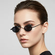 Woman wearing black retro sunglasses against a light grey background