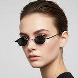 Woman wearing black retro sunglasses against a light grey background