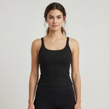 Woman wearing a black ribbed tank top against a plain background