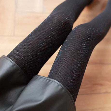Black shiny collant worn by a person on a wooden surface