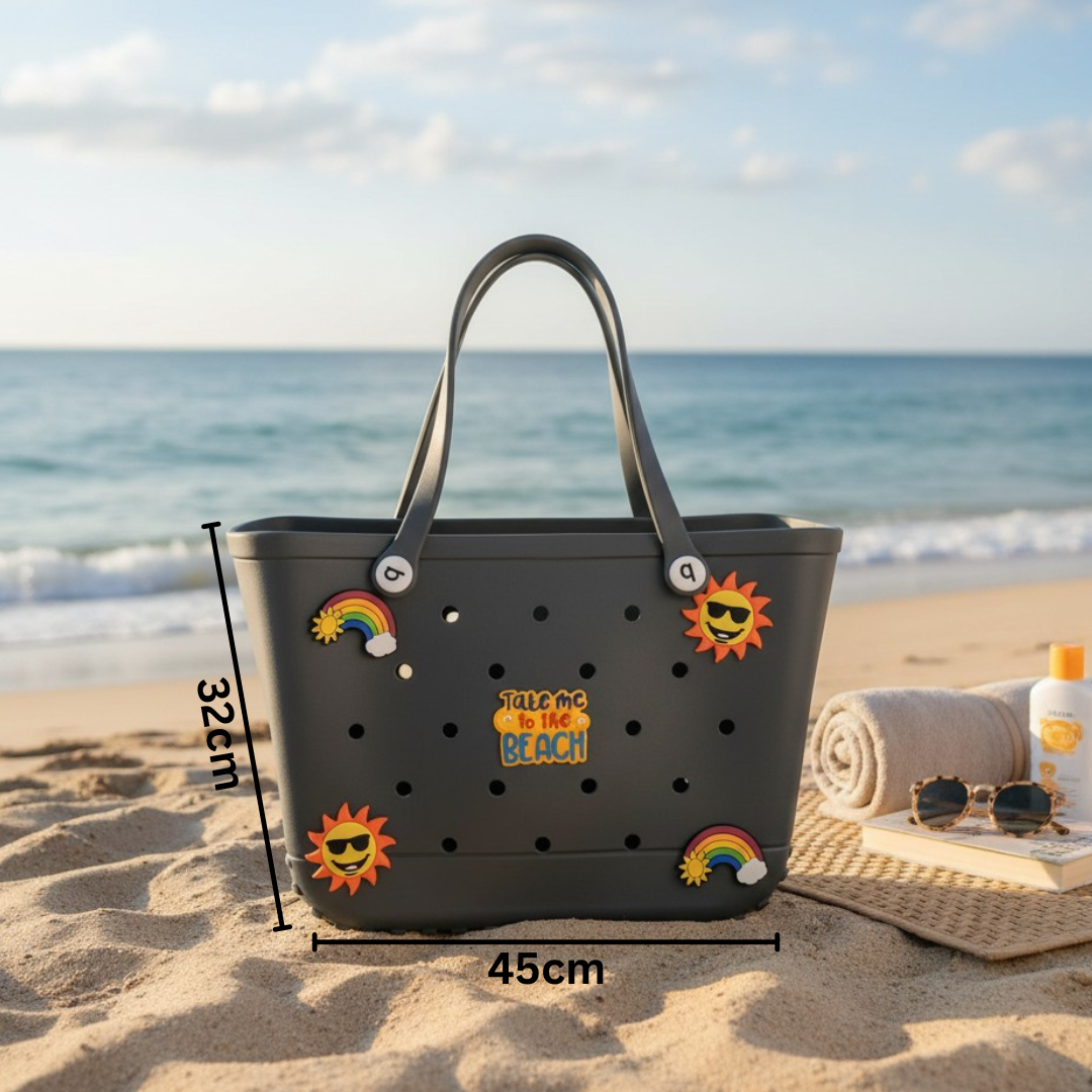 Black beach bag with colorful stickers on a sandy beach with ocean view
