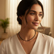 Woman wearing a black beaded necklace in a softly lit room