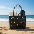 Black tote bag with colorful embellishments on a dark surface